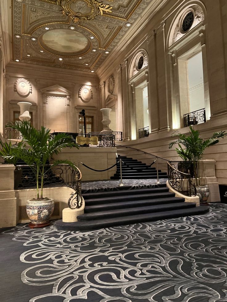 an ornately decorated lobby with stairs and planters on either side of the staircase