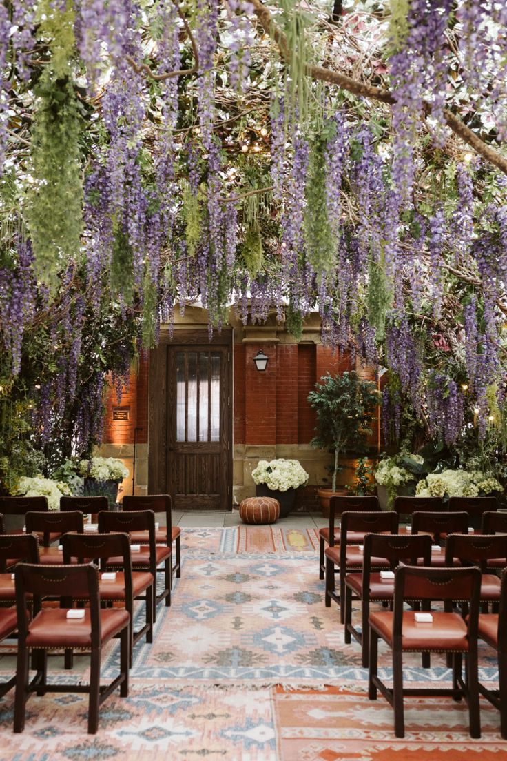 an outdoor ceremony setup with chairs and flowers hanging from the ceiling in front of it