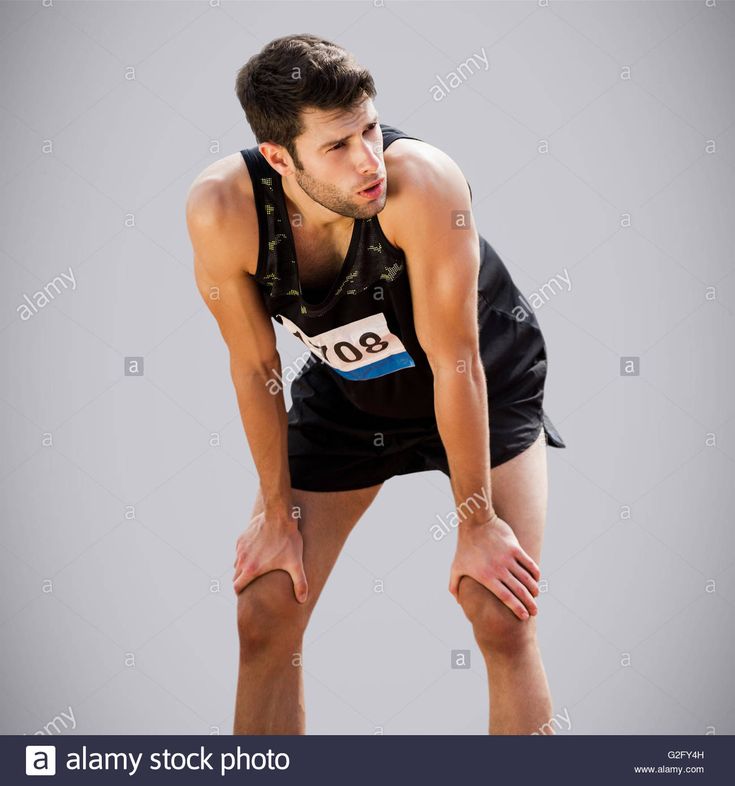 a man in black shirt and shorts standing with his hands on his knees while looking down at the ground