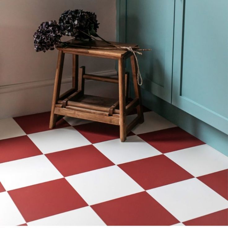 a wooden stool sitting on top of a red and white checkered floor next to a blue cabinet