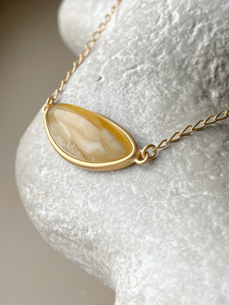 Embrace the captivating allure of the Baltic sea with this chic, elliptical amber pendant. Each piece showcases a pristine slice of natural Baltic amber, renowned for its warmth and depth, encased in a sophisticated gold-plated sterling silver frame. This pendant is the essence of elegance, designed to add a touch of timeless sophistication to any outfit. Its unique organic patterns ensure that no two pendants are alike, offering you an exclusive piece of the earth's beauty. Sterling silver, amber, gold plated Chain length 15 - 16.5" Stone size 1,06" Weight 0,22 oz Organic Patterns, Organic Pattern, Amber Pendant, Gold Nugget, Baltic Sea, Baltic Amber, Gold Plated Chains, Silver Frame, Gold Plated Sterling Silver