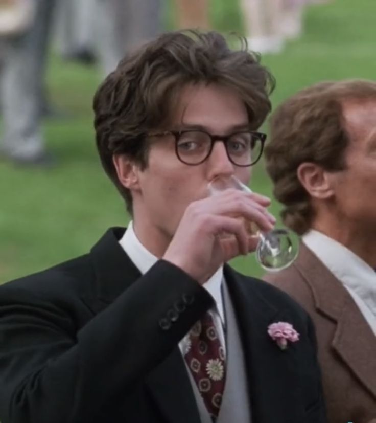 two men in suits are drinking from wine glasses