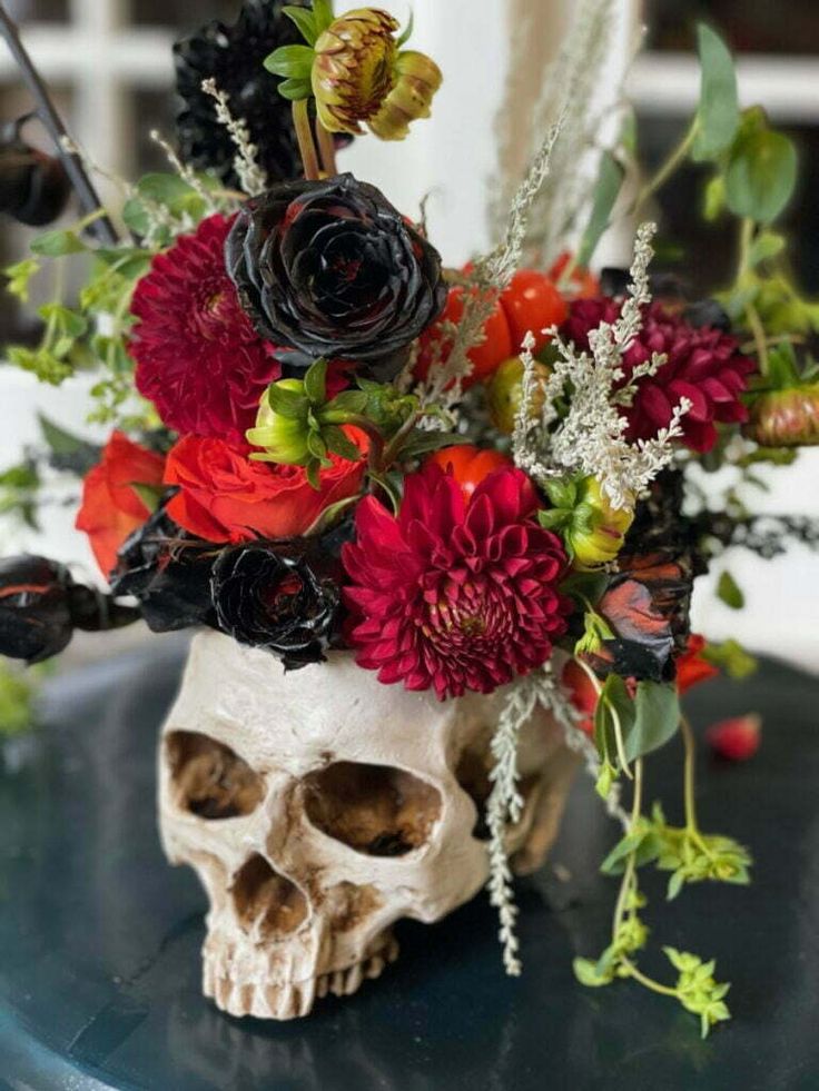 a skull with flowers in it sitting on a table