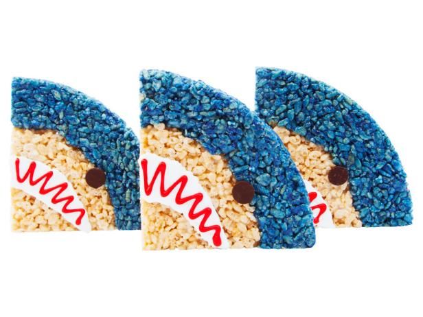 three shark shaped rice krispy treats with blue and white sprinkles on them