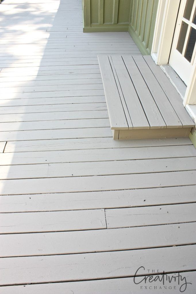 a wooden porch with white paint and green shutters