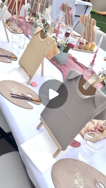 the table is set up for an event with place settings and decorations on it, including t - shirts