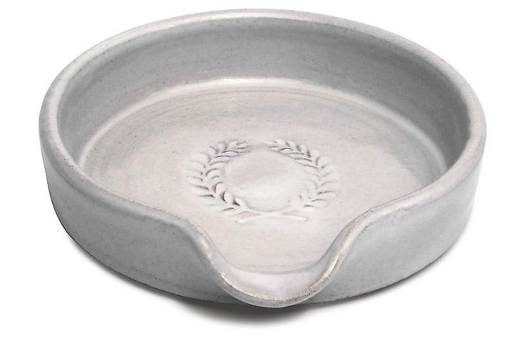 a white bowl with an oval design on the bottom and a laurel decoration in the middle