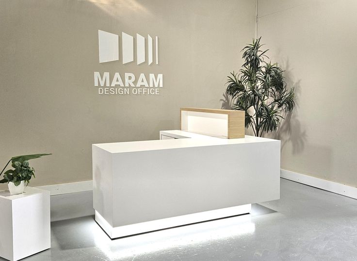 a white reception desk sitting next to a potted plant on top of a table