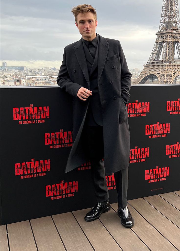 a man standing in front of a wall with the eiffel tower in the background