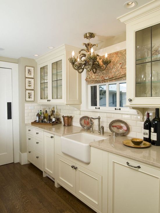 a large kitchen with white cabinets and wooden floors is pictured in this image, there are wine bottles on the counter