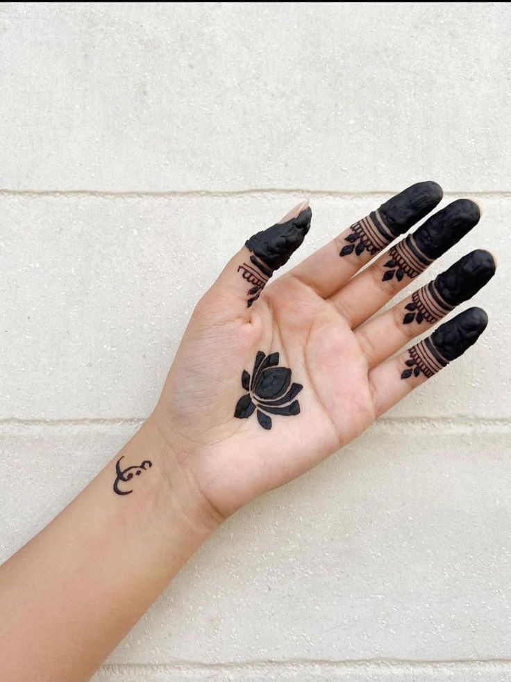 a woman's hand with black hennap and tattoos on her left palm