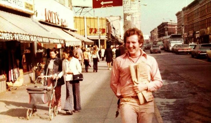 a man is walking down the street with his hand in his pocket and smiling at the camera