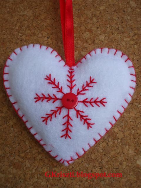 a white and red snowflake heart ornament hanging on a cork board