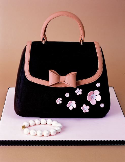 a birthday cake with a handbag and candy on the top, decorated with flowers