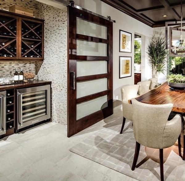 the dining room table is surrounded by chairs and wine bottles on display behind glass doors