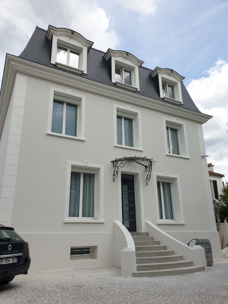 a large white building with stairs leading up to the front door and two story windows