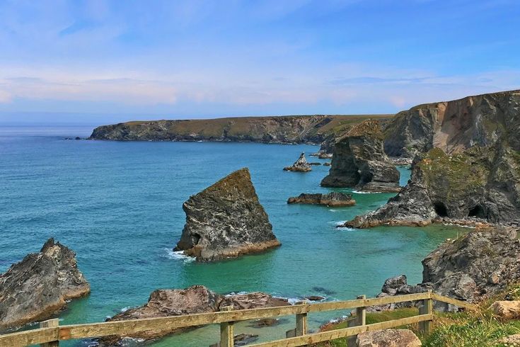 a wooden fence overlooks the ocean and rocky coastline with large rocks on either side