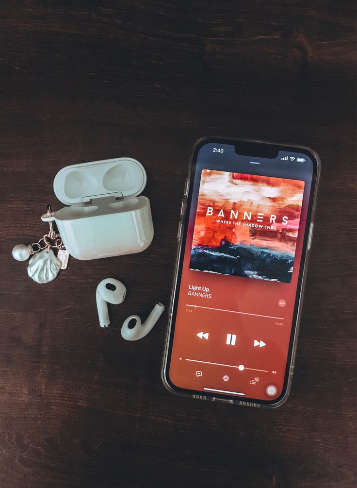 an iphone and ear buds sitting on top of a wooden table