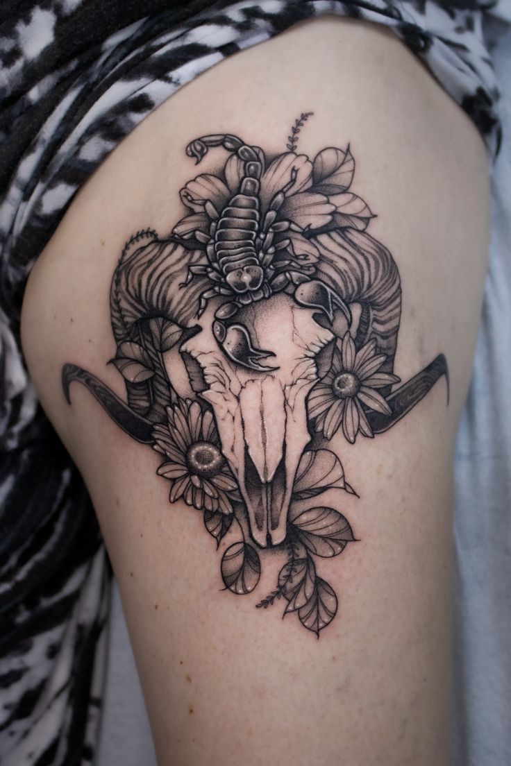 a woman's thigh with a bull skull and flowers on it