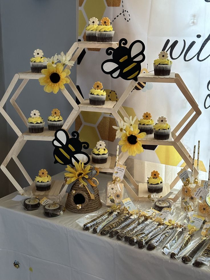 a table topped with cupcakes covered in frosting next to a honeycomb