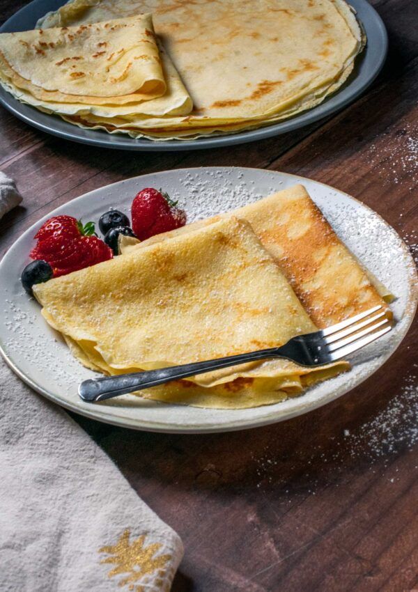 two plates with crepes and strawberries on them