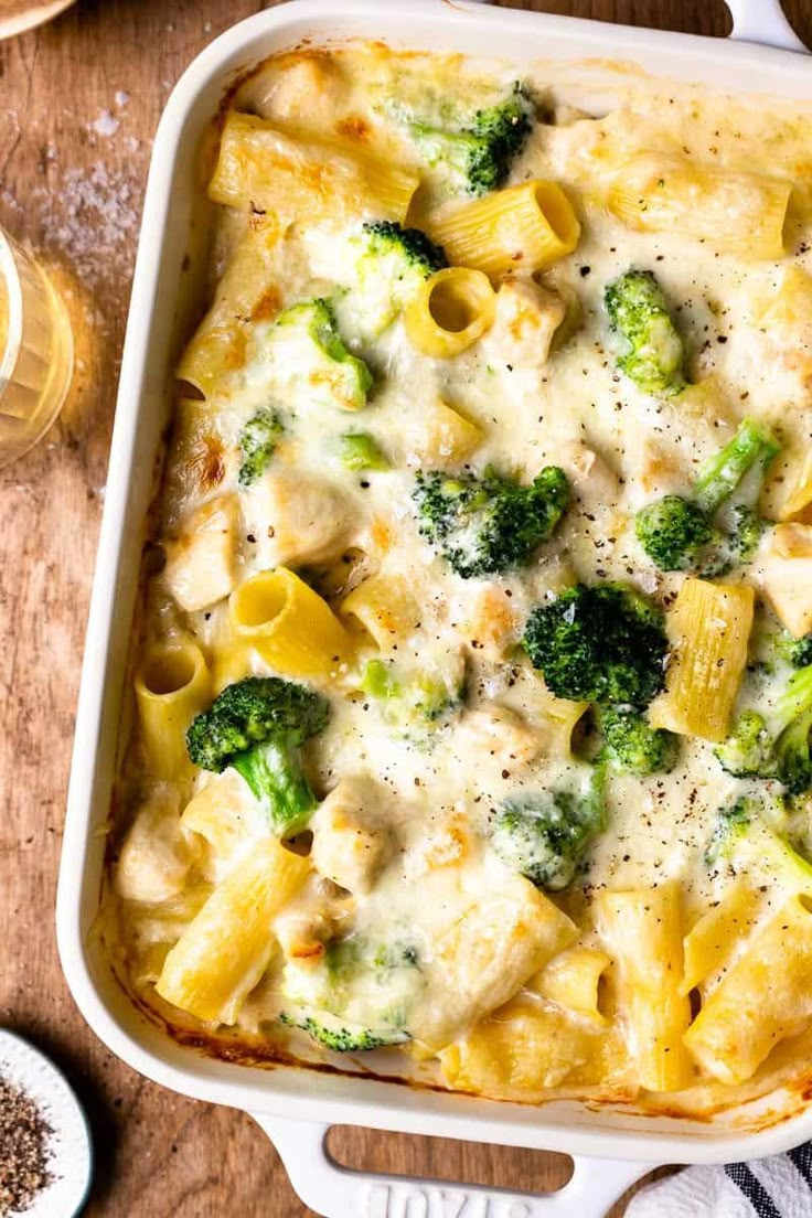 a casserole dish with broccoli and cheese in it on a wooden table