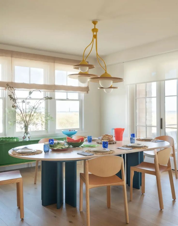 a dining room table with chairs and plates on it in front of two large windows