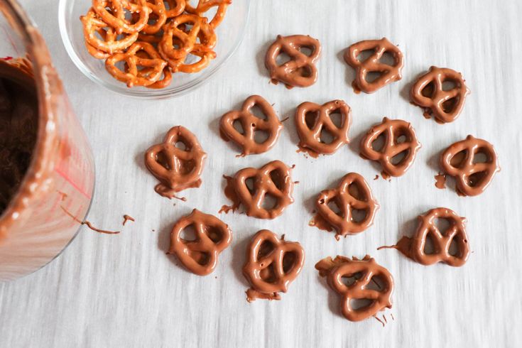 some pretzels are sitting on a table next to a bowl of chocolate