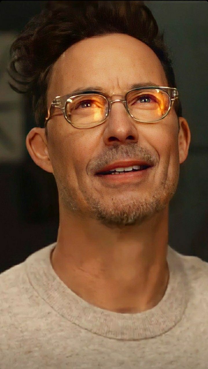 a man wearing glasses and smiling at the camera