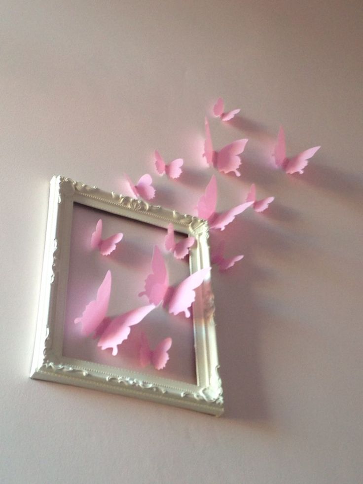 some pink butterflies are flying out of a white frame on the wall in front of a mirror