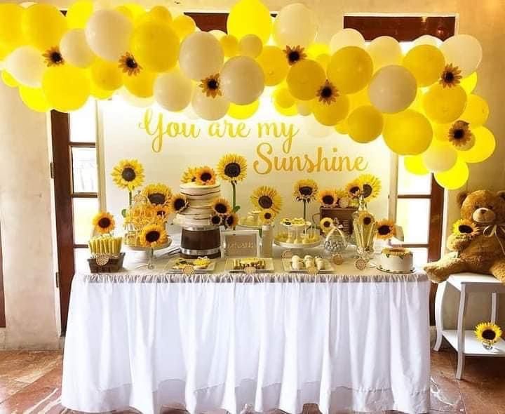 a table with sunflowers and balloons on it