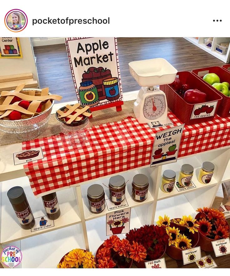 an apple market display with apples, sunflowers and other fruit on the table