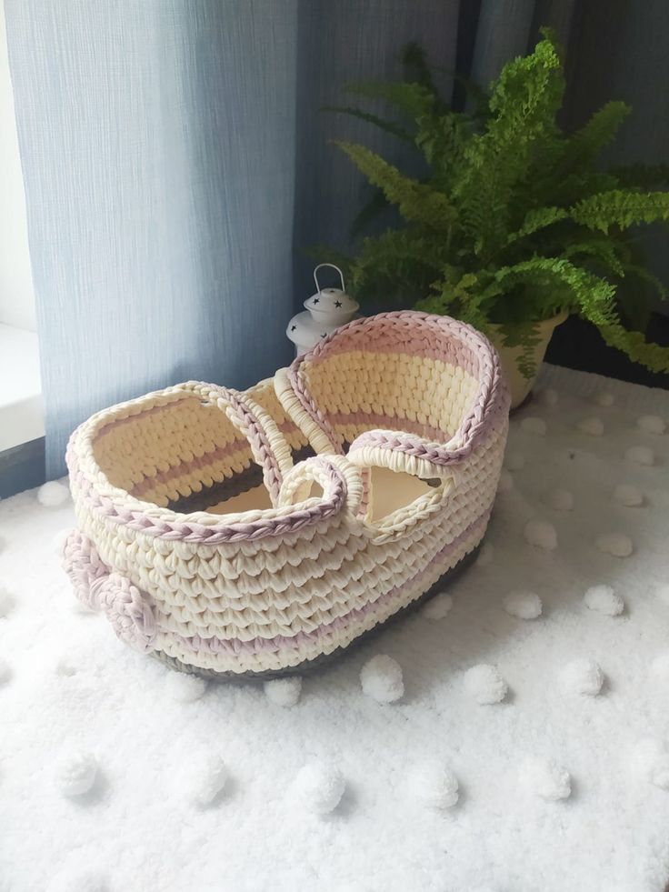 a crocheted basket sitting next to a potted plant on a window sill