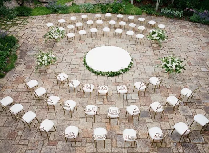 an aerial view of a wedding ceremony setup with white chairs and flowers on the ground