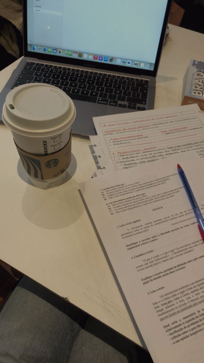 a cup of coffee sitting on top of a table next to an open laptop computer