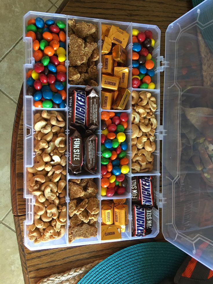 a plastic container filled with lots of different types of candy and candies on top of a wooden table