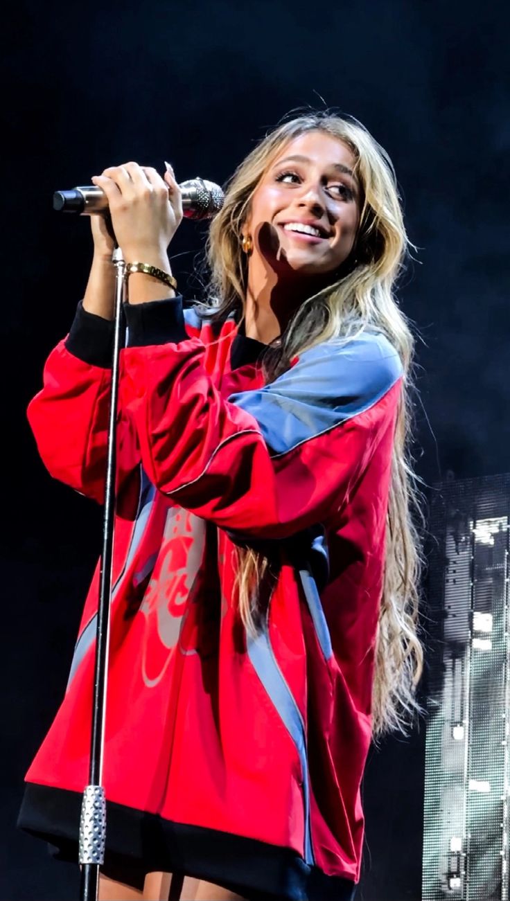 a woman holding a microphone on top of a stage