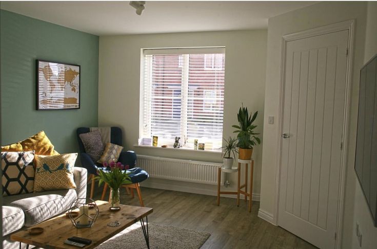 a living room filled with furniture and a window covered in blinds on the windowsill