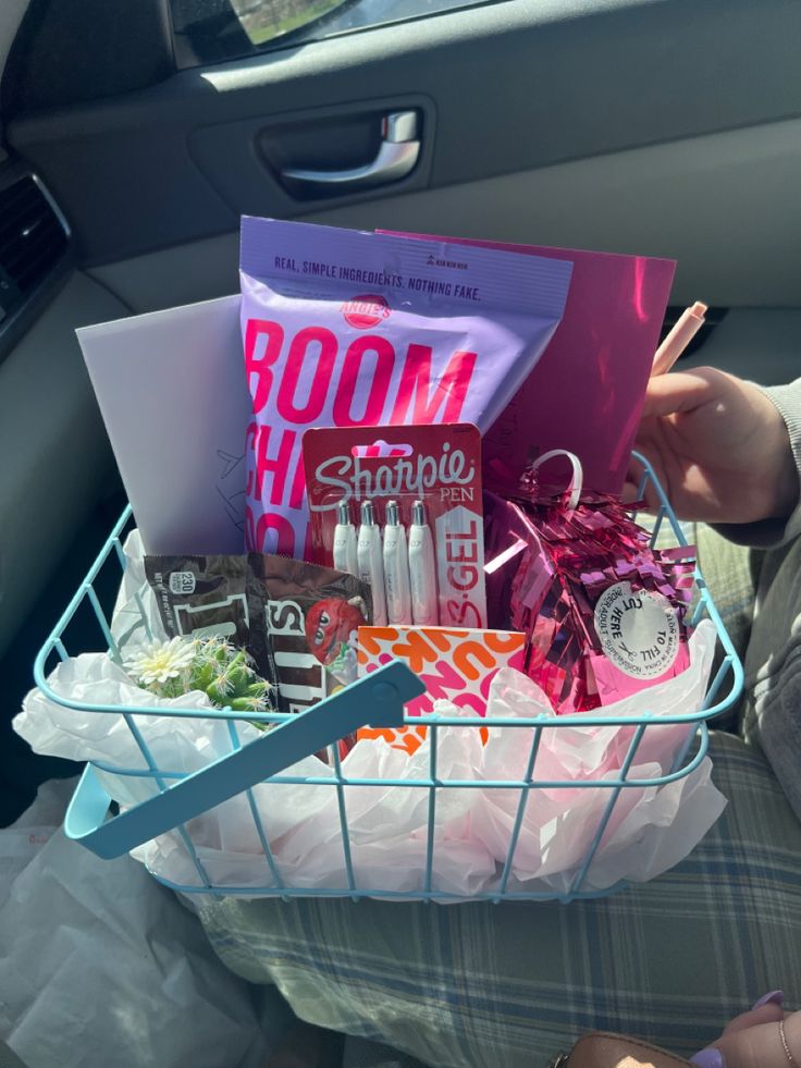 a basket filled with lots of items in the back seat of a car next to a woman's hand