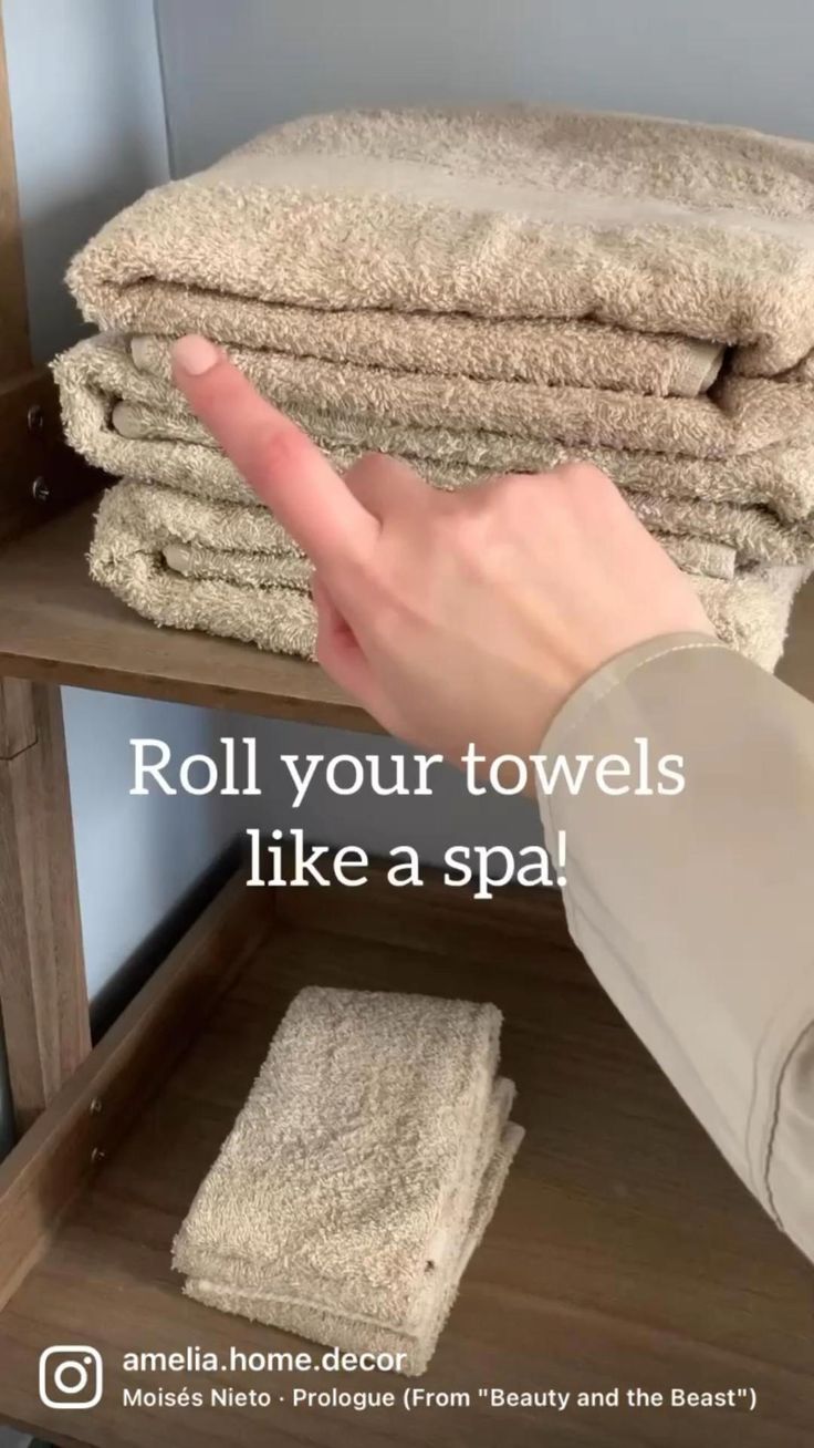 a person is pointing at towels stacked on top of each other with the words roll your towels like a spa