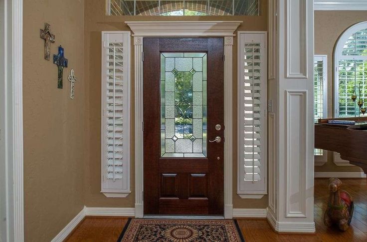 an entryway with shutters and a rug on the floor