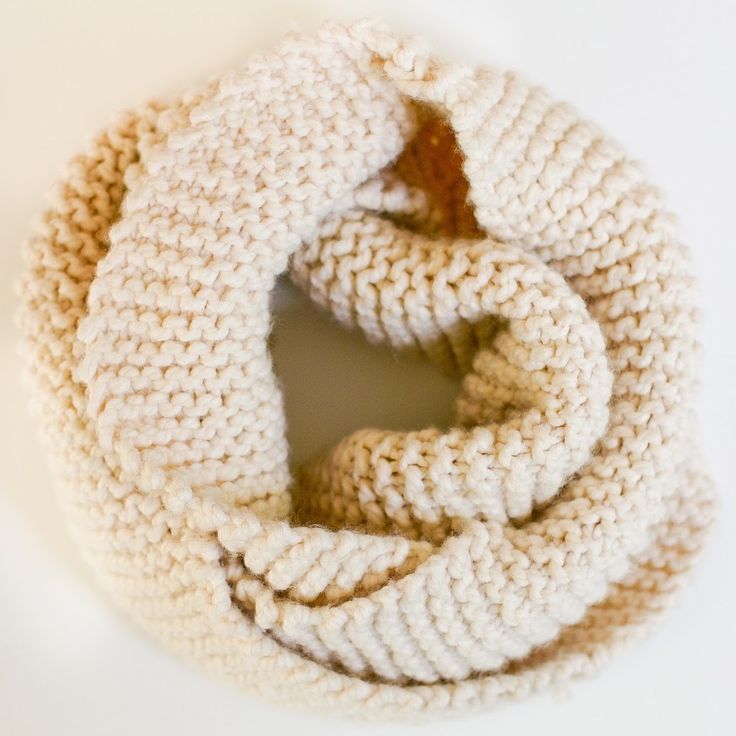 a white knitted scarf on a white surface with a circular hole in the middle