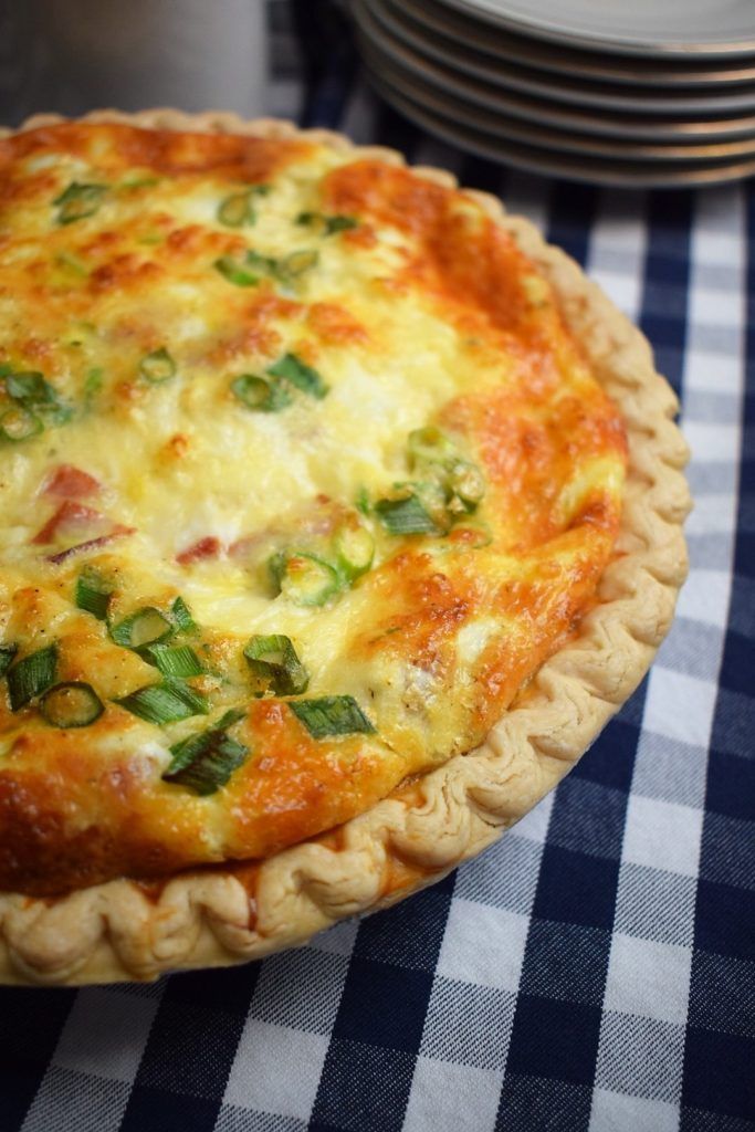 a cheesy quiche on a blue and white checkered table cloth