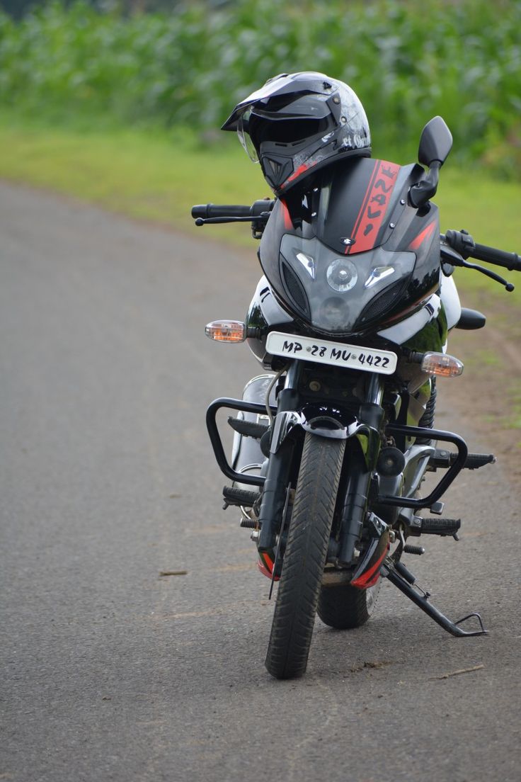 the motorcycle is parked on the side of the road with its helmet on it's back end