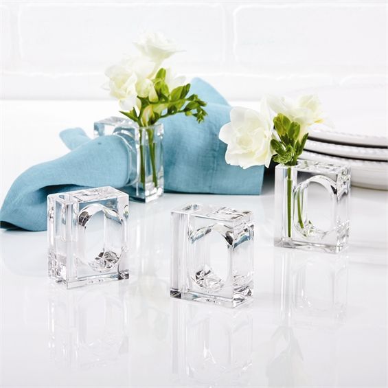 three clear vases with flowers in them on a white tablecloth and blue napkin