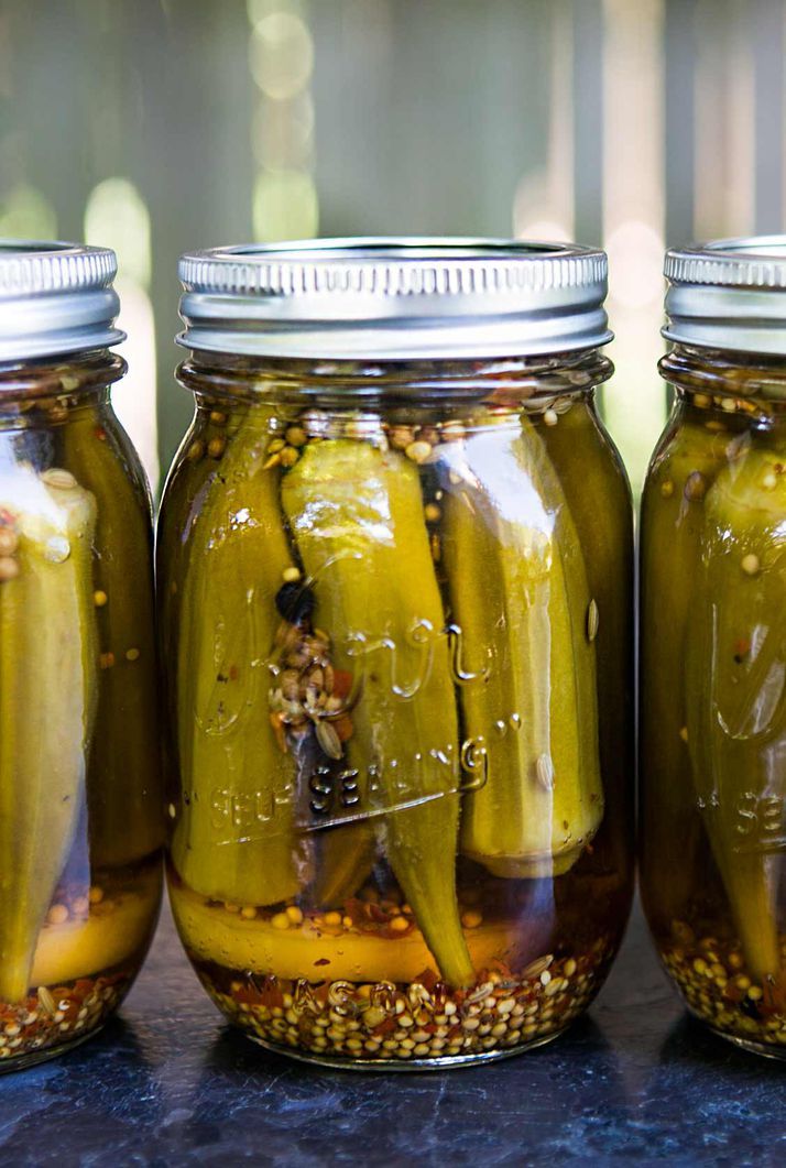 three jars filled with pickles sitting on top of a table