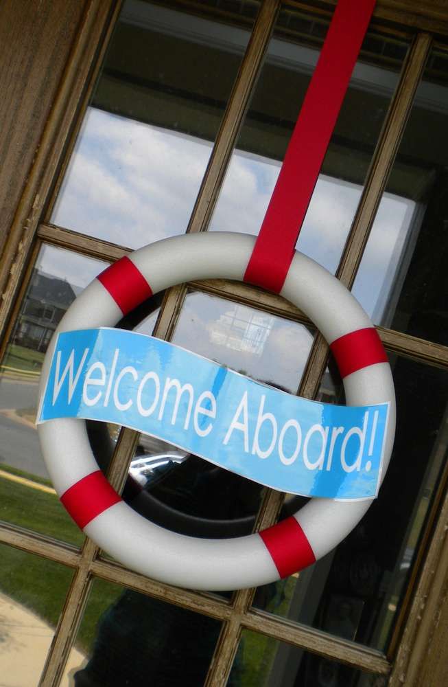 a welcome aboard sign hanging from the side of a door with a life preserver