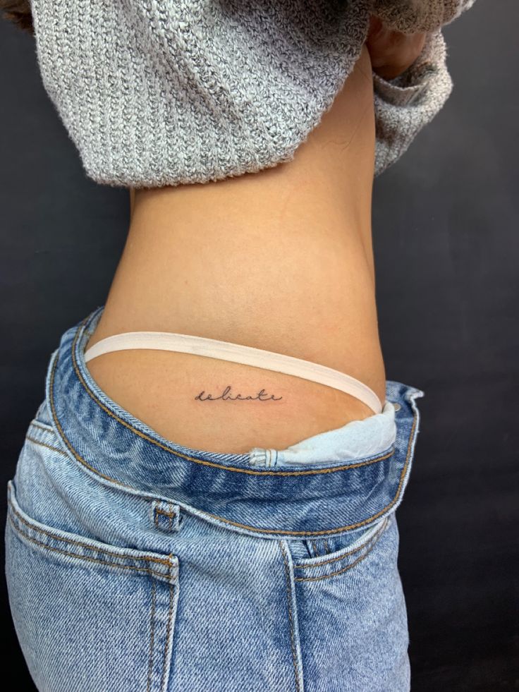 a woman's lower back tattoo with the word believe written on her left side