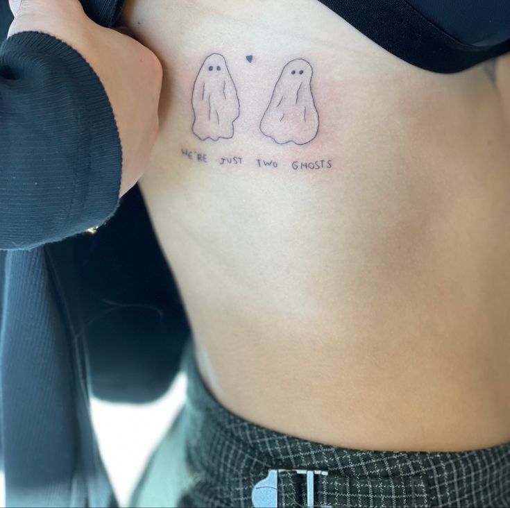 a woman's stomach with two ghost tattoos on her belly and the words, ghosts don't bite you