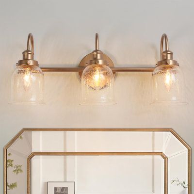 a bathroom vanity with two lights and a mirror on the wall next to it,